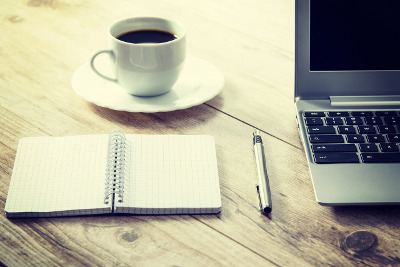 Laptop, Notizblock und Kaffeetasse